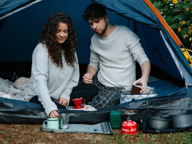 Happy camper sitting up in a sleeping bag inside a tent with morning light