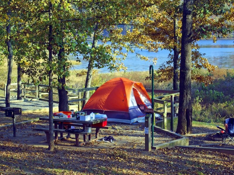 Camping essentials laid out on a blanket beside a tent at sunset